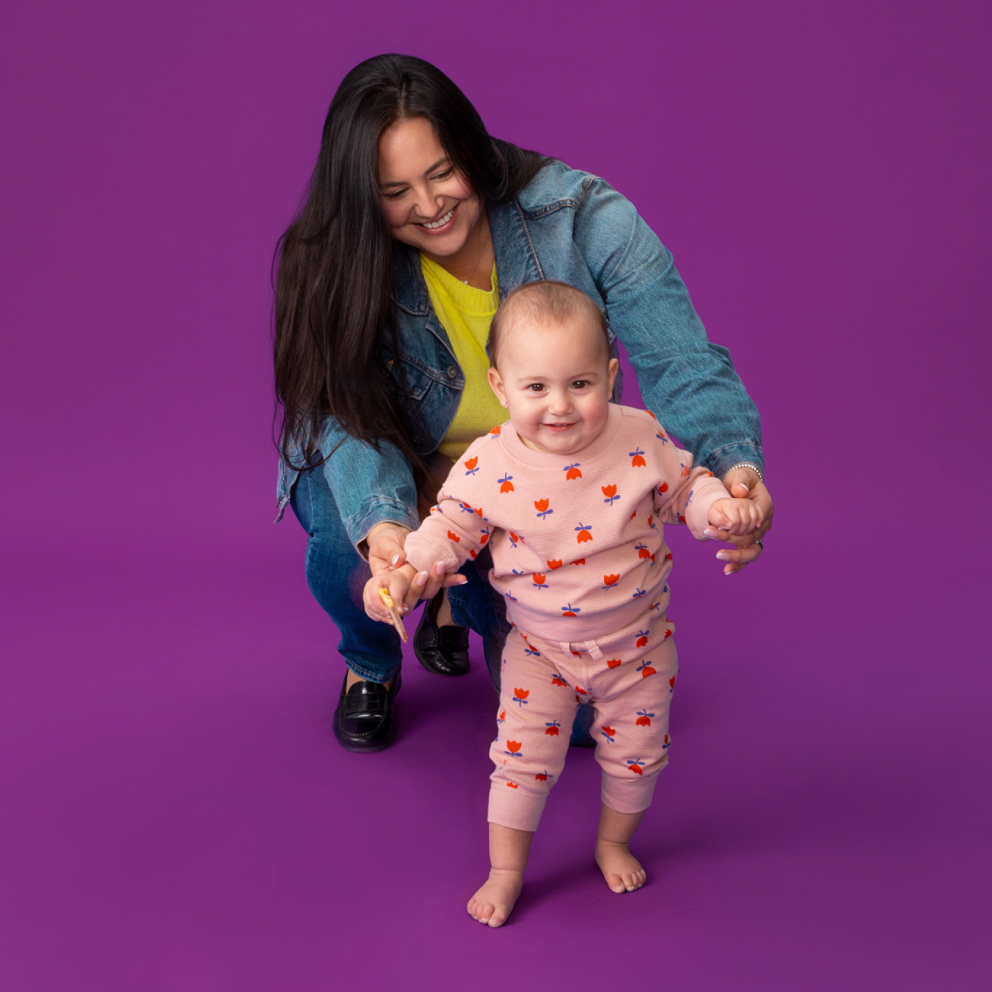 mother supporting smiling baby walking