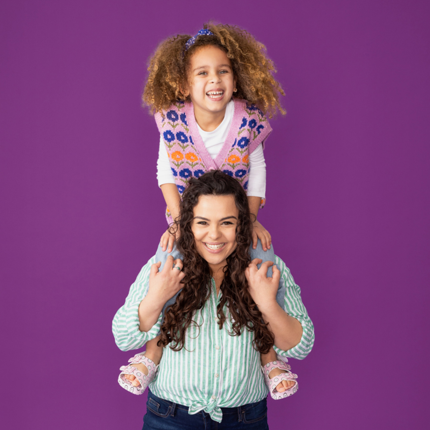 daughter smiling, sitting on smiling mother's shoulders